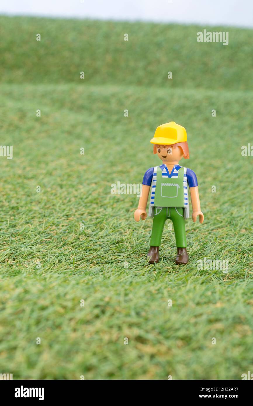 Kleines Spielzeug Playmobil Landwirt Figur steht in "Feld" aus faux / gefälschte Gras. Für die britische Lebensmittelproduktion: Farm to Fork, Field to Fork / Field to Plate. Stockfoto