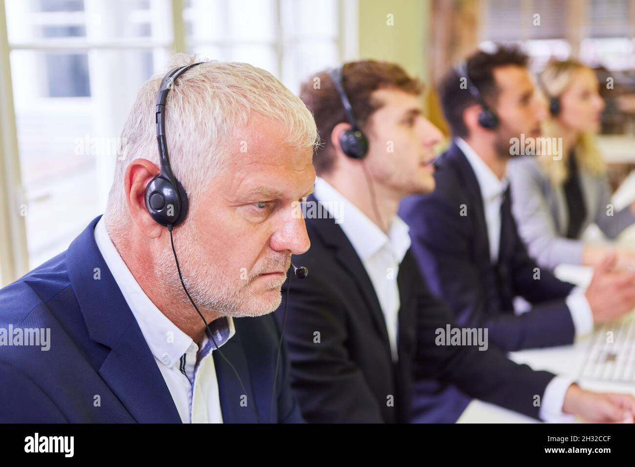 Mitarbeiter des Geschäftsteams mit Headset während einer Schulung für die Hotline im Call Center Stockfoto