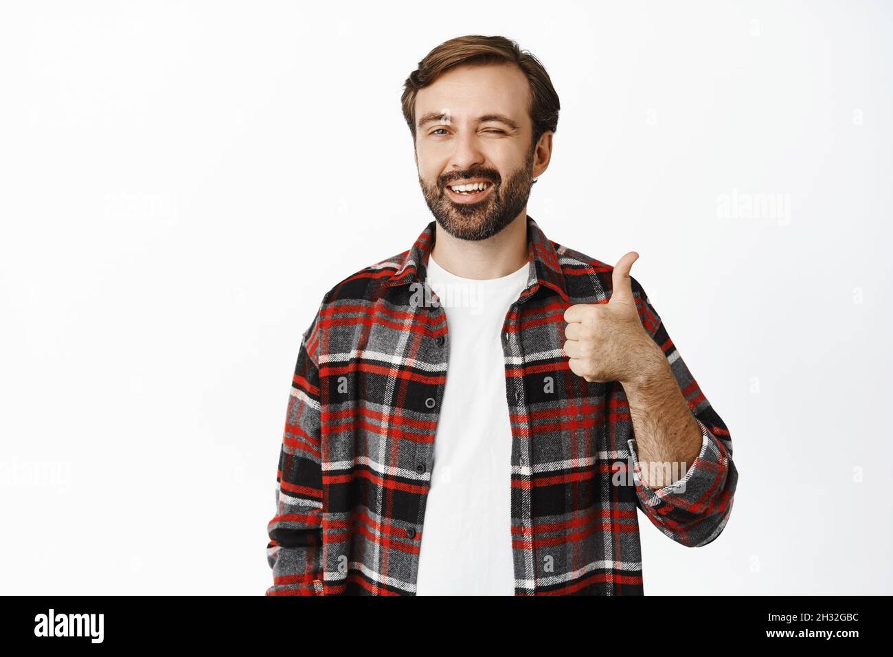 Gutaussehender lächelnder Familienmensch zwinkerte und zeigte Daumen nach oben, empfahl Produkt, Lob und mag Promo-Angebot, stand auf weißem Hintergrund Stockfoto