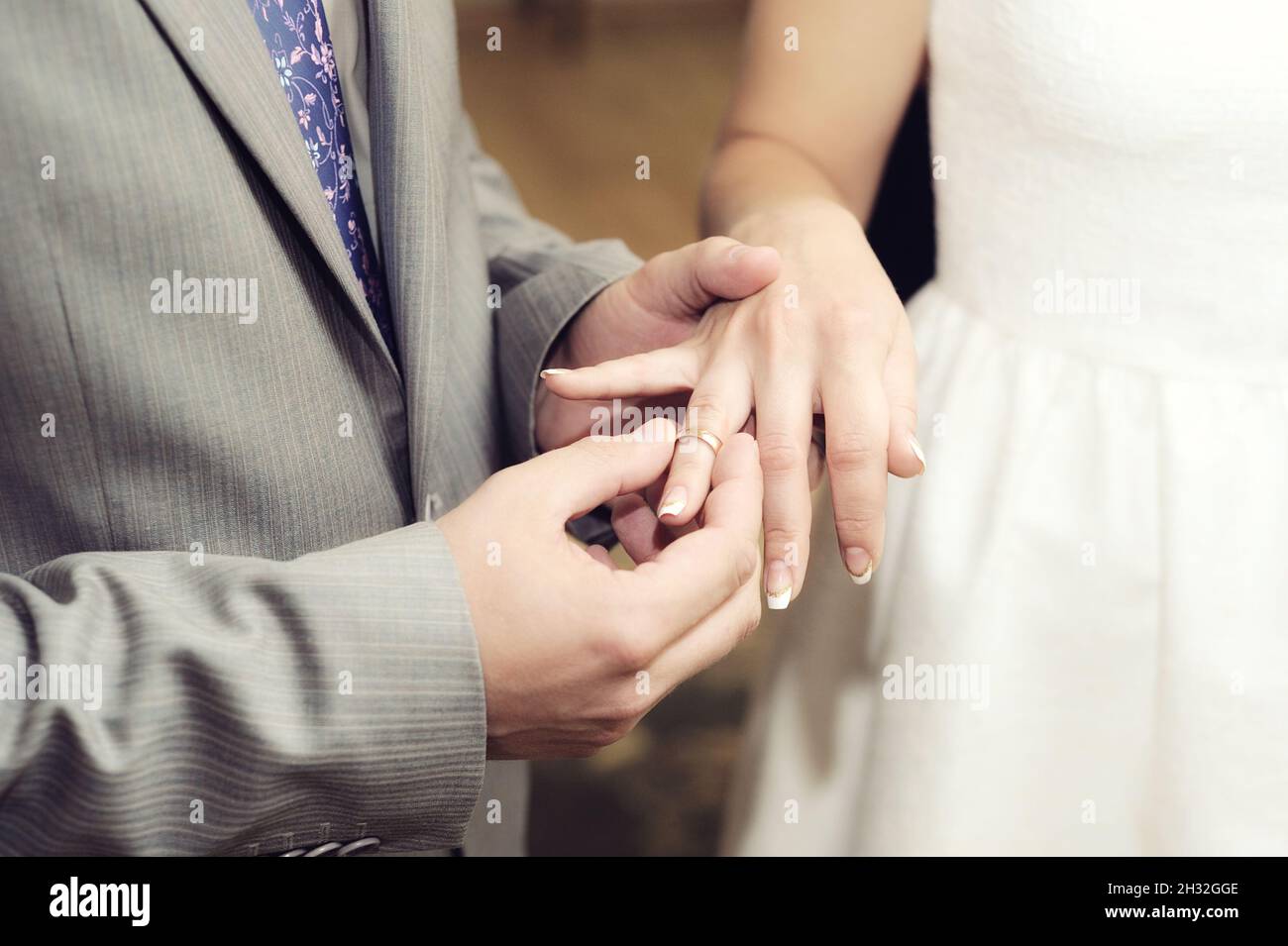 Austausch Von Eheringen. Hochzeitszeremonie. Der Bräutigam legt den goldenen Ehering an den Finger des Brautpaares, aus der Nähe. Braut und Bräutigam, Brautpaar. Stockfoto