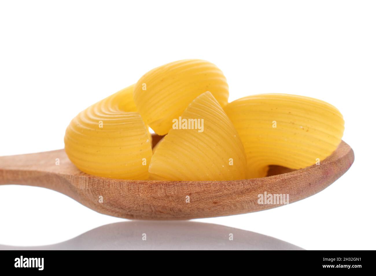 Hellgelbe, ungekochte Pasta mit einem Holzlöffel, Nahaufnahme, isoliert auf Weiß. Stockfoto