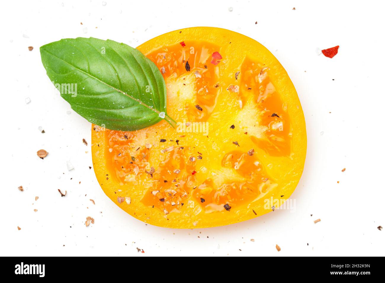 Gelbe Tomatenscheibe mit Basilikum und Gewürzen, Pfeffer, Salz. Komposition isoliert auf weißem Hintergrund. Draufsicht. Flach liegend Stockfoto