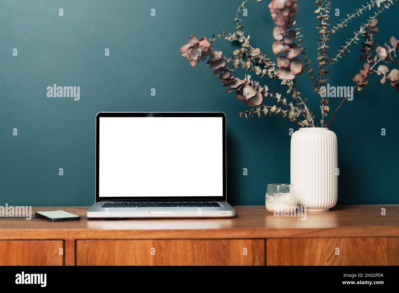 Laptop-Computer mit leerem leerem, leerem Mockup-Bildschirm über smaragdgrünem, modernem Wohnzimmerdesign. Heimbüro, Arbeitsplatz, Arbeit oder Studium von zu Hause aus, aus der Ferne Stockfoto