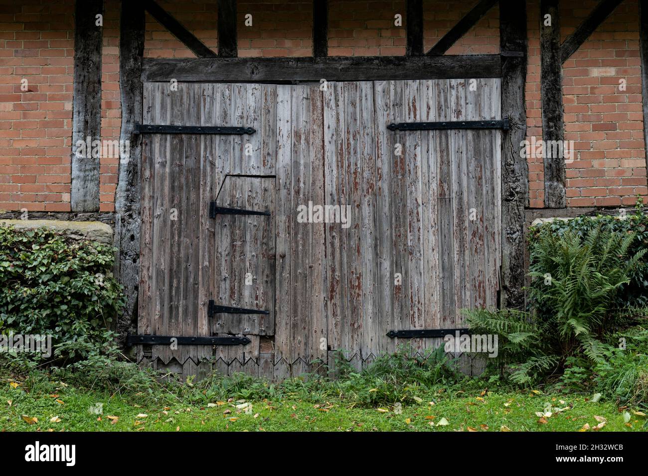 Schöne alte hölzerne Scheunentür mit Metallscharnieren und kleiner Eingangstür Stockfoto