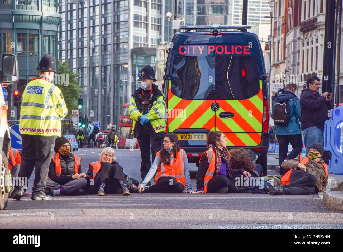 London, Großbritannien. Oktober 2021. Demonstranten sitzen während der Demonstration auf der Straße.Beleidigung Großbritanniens Demonstranten klebten sich an die Straße und blockierten die Wormwood Street und Bishopsgate in der Nähe des Bahnhofs Liverpool Street. Der Protest besteht darin, die Regierung zu fordern, bis 2030 alle Häuser im Vereinigten Königreich zu isolieren, um die CO2-Emissionen zu senken. Kredit: SOPA Images Limited/Alamy Live Nachrichten Stockfoto