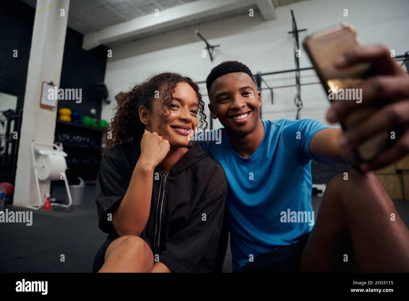 Afroamerikanische Freunde sitzen auf dem Boden und machen gemeinsam ein Foto am Telefon. Afroamerikanisches Paar, das zusammen ein Selfie gemacht hat. Hohe Qualität Stockfoto