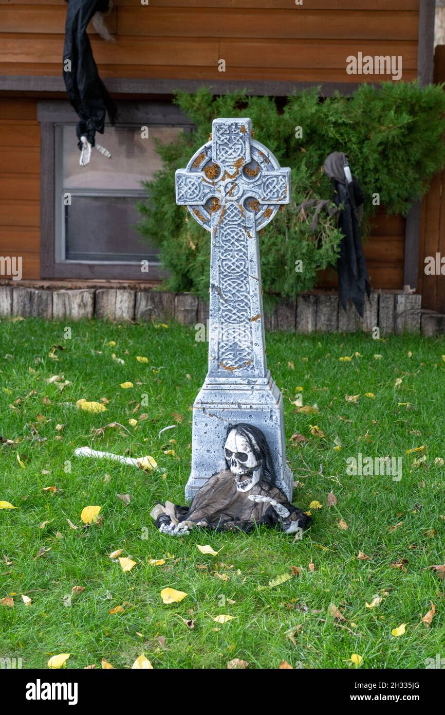 Ein ghoulisches Skelett, das aus einem Grab in einer Halloween-Rasendekoration hervortritt. Stockfoto