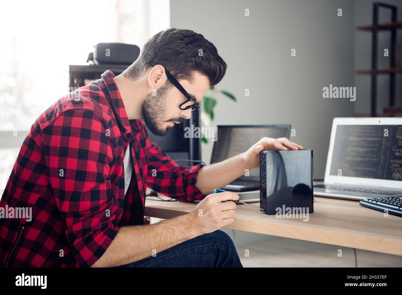 Profil Seitenansicht Porträt von attraktiven fokussierten erfahrenen Kerl Fixierung Detail macht Upgrade am Arbeitsplatz Station in Innenräumen Stockfoto