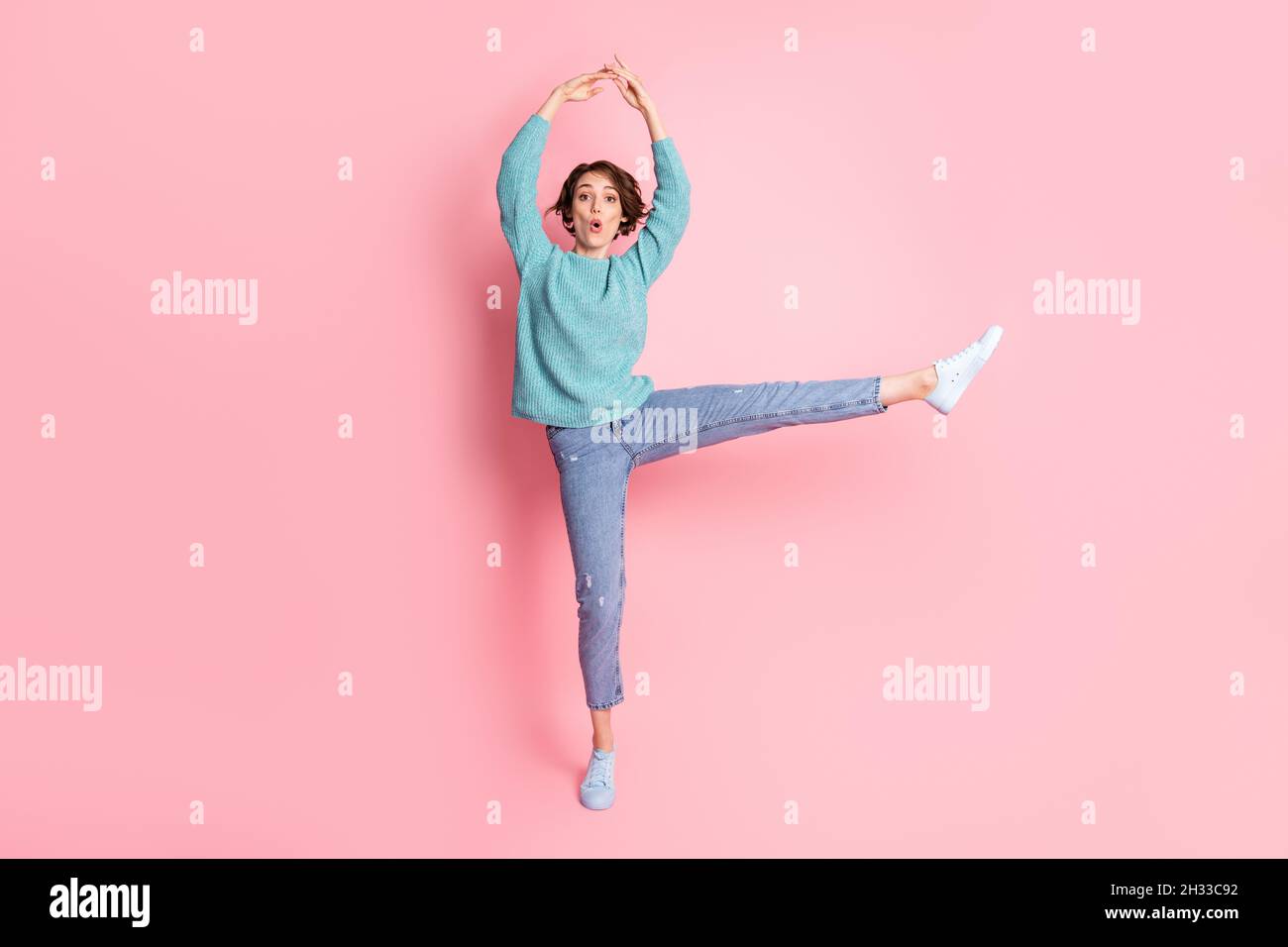 Ganzkörper-Foto von jungen aufgeregt Frau heben Hände Beine Ballett isoliert auf pastellrosa Hintergrund Stockfoto