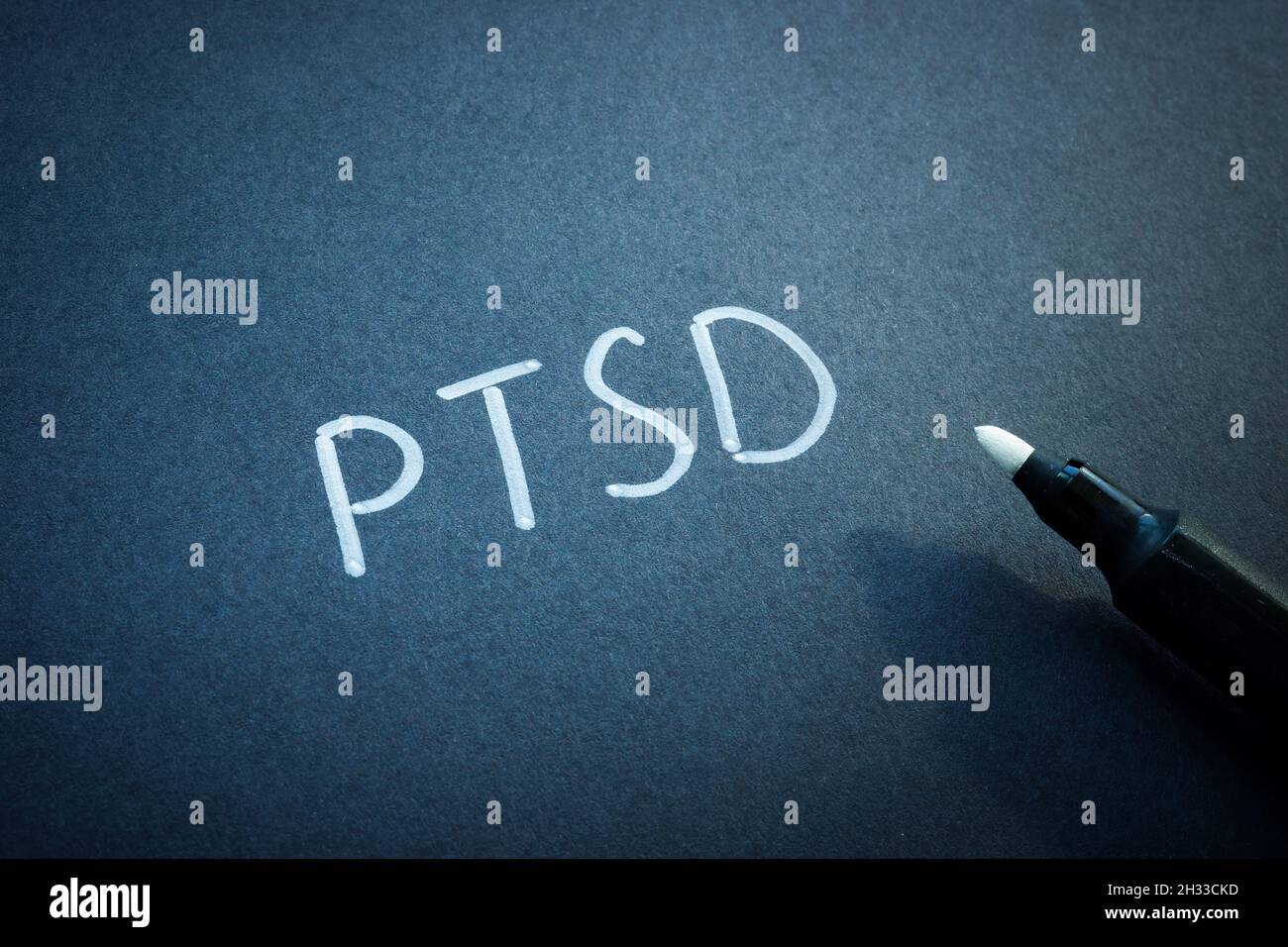 PTSD oder posttraumatische Belastungsstörung handgeschrieben auf dem schwarzen Blatt Papier. Stockfoto