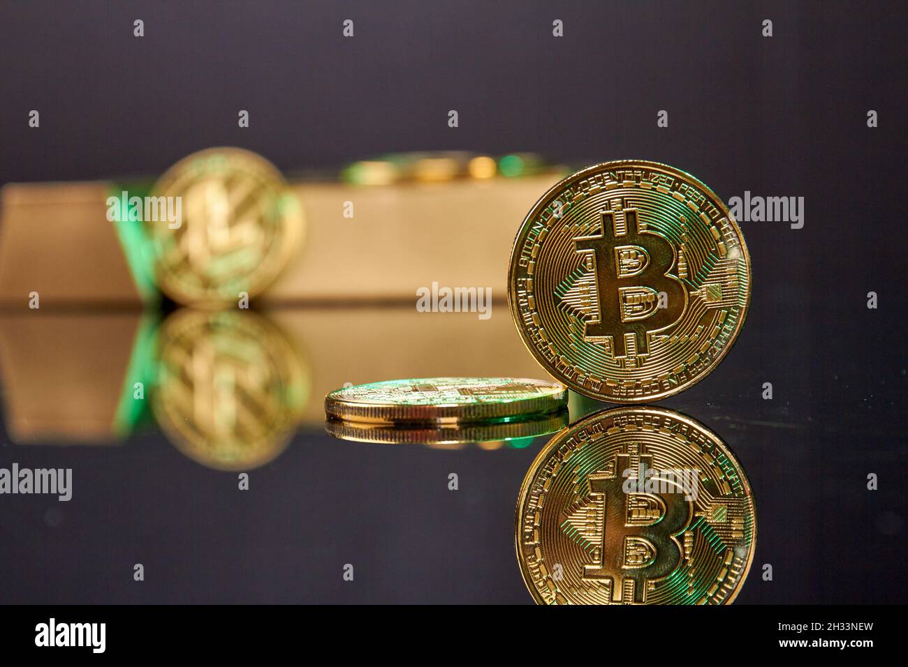 Stehende Bitcoin-Münze auf dem reflektierenden Schreibtisch. Stockfoto