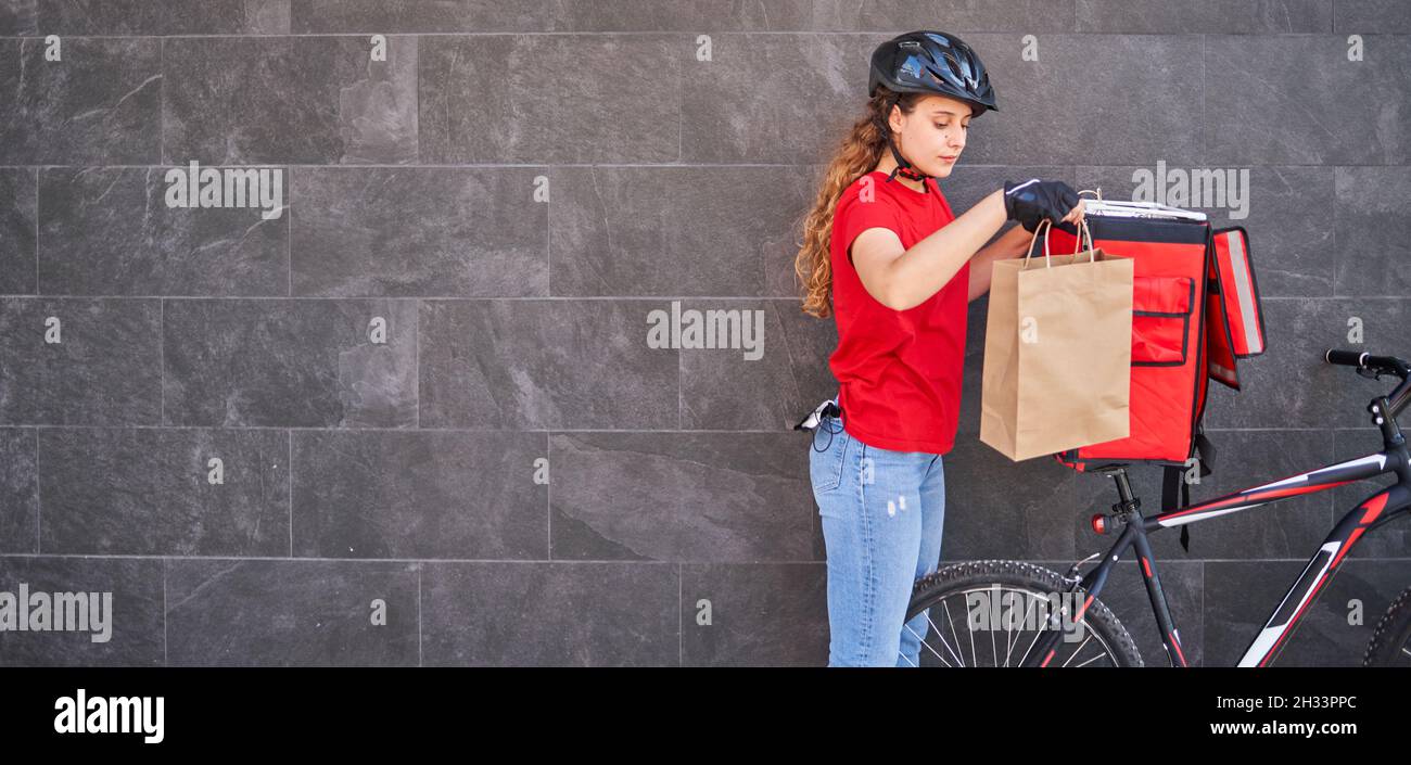 Eine Radfahrerin nimmt die Bestellung aus dem Rucksack Stockfoto