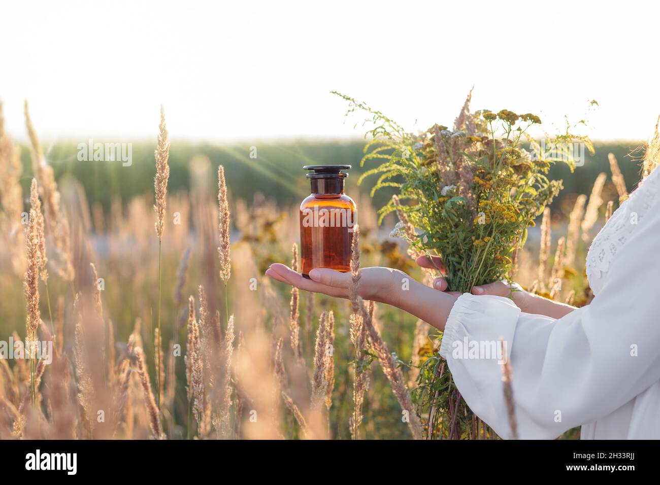 Eine alte medizinische Flasche in der Hand einer Frau, Kräuterkundige. Kräutermedizin - Konzept. Stockfoto