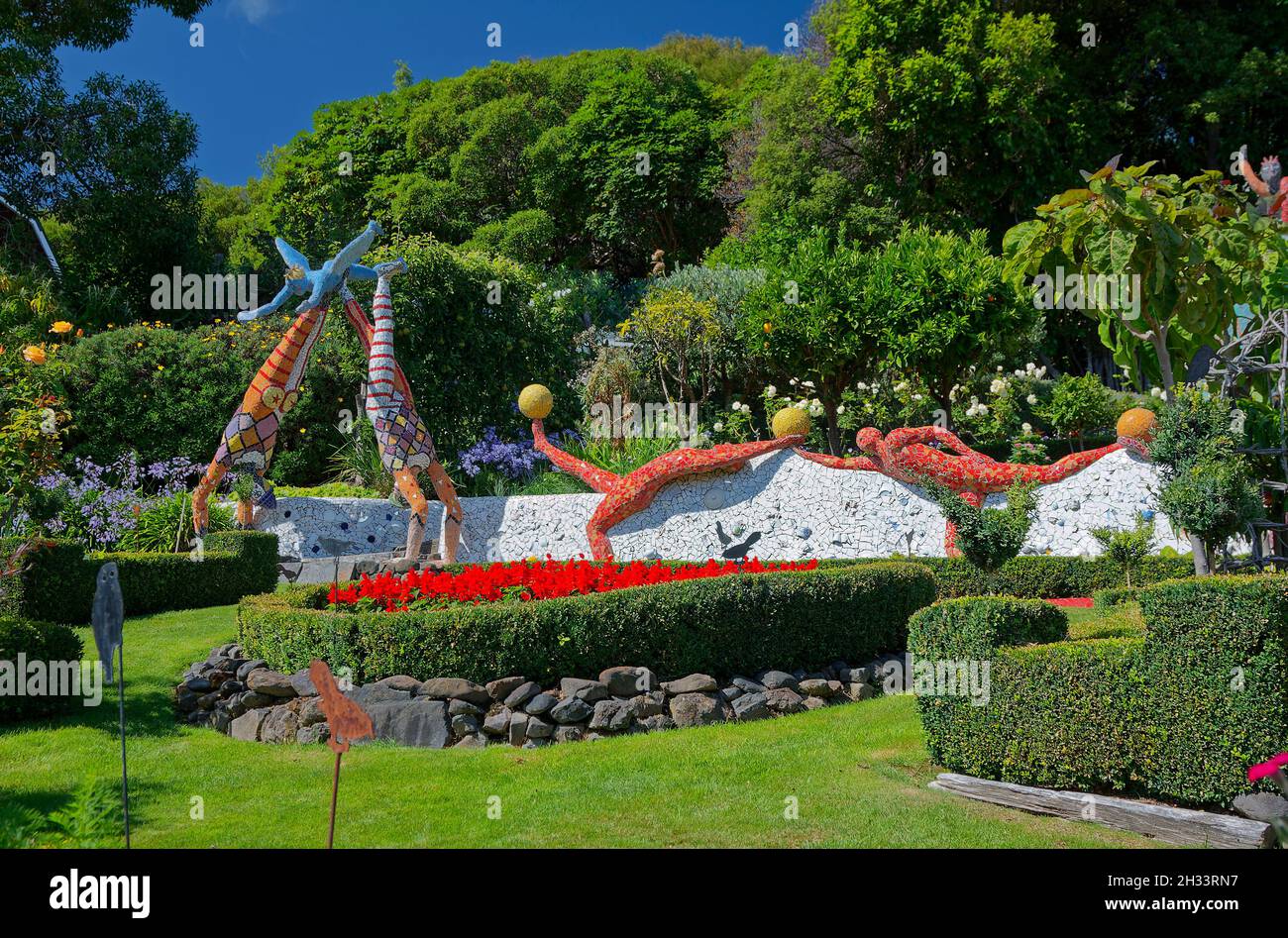 Gartenszene, große Mosaikfliesen Dekorationen, Akrobaten, Fußballspieler, Blumen, Bäume, Sträucher, grünes Gras, skurril, bunt, einzigartig, Akaroa; New Z Stockfoto