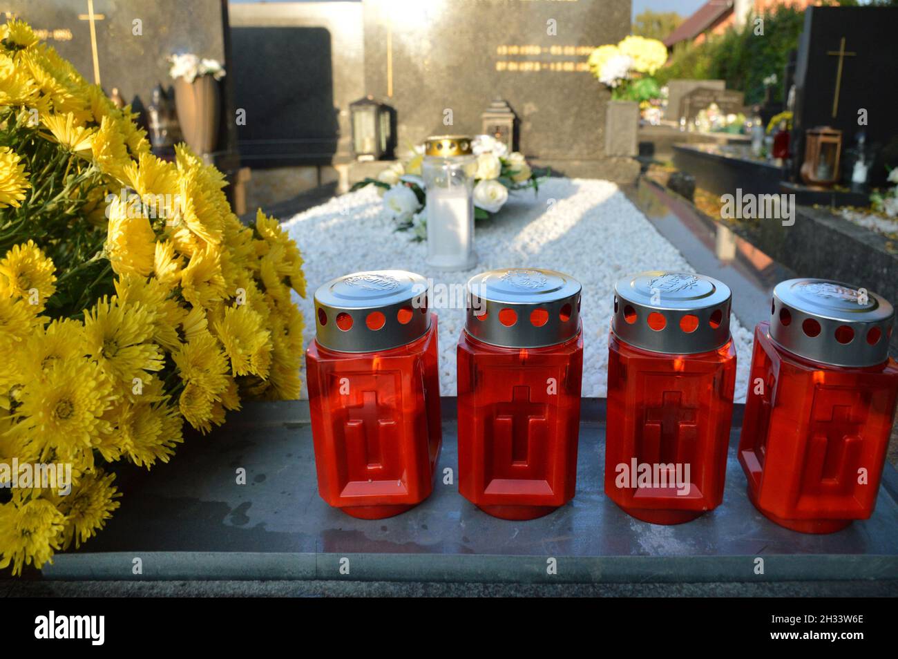 Rote Votivkerzen und Blumen auf dem Grab Stockfoto