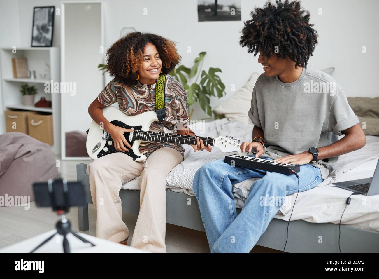 Porträt zweier afroamerikanischer junger Menschen, die zu Hause Musik spielen und Video oder Livestream aufnehmen, Bruder- und Schwesterkonzept, Kopierraum Stockfoto