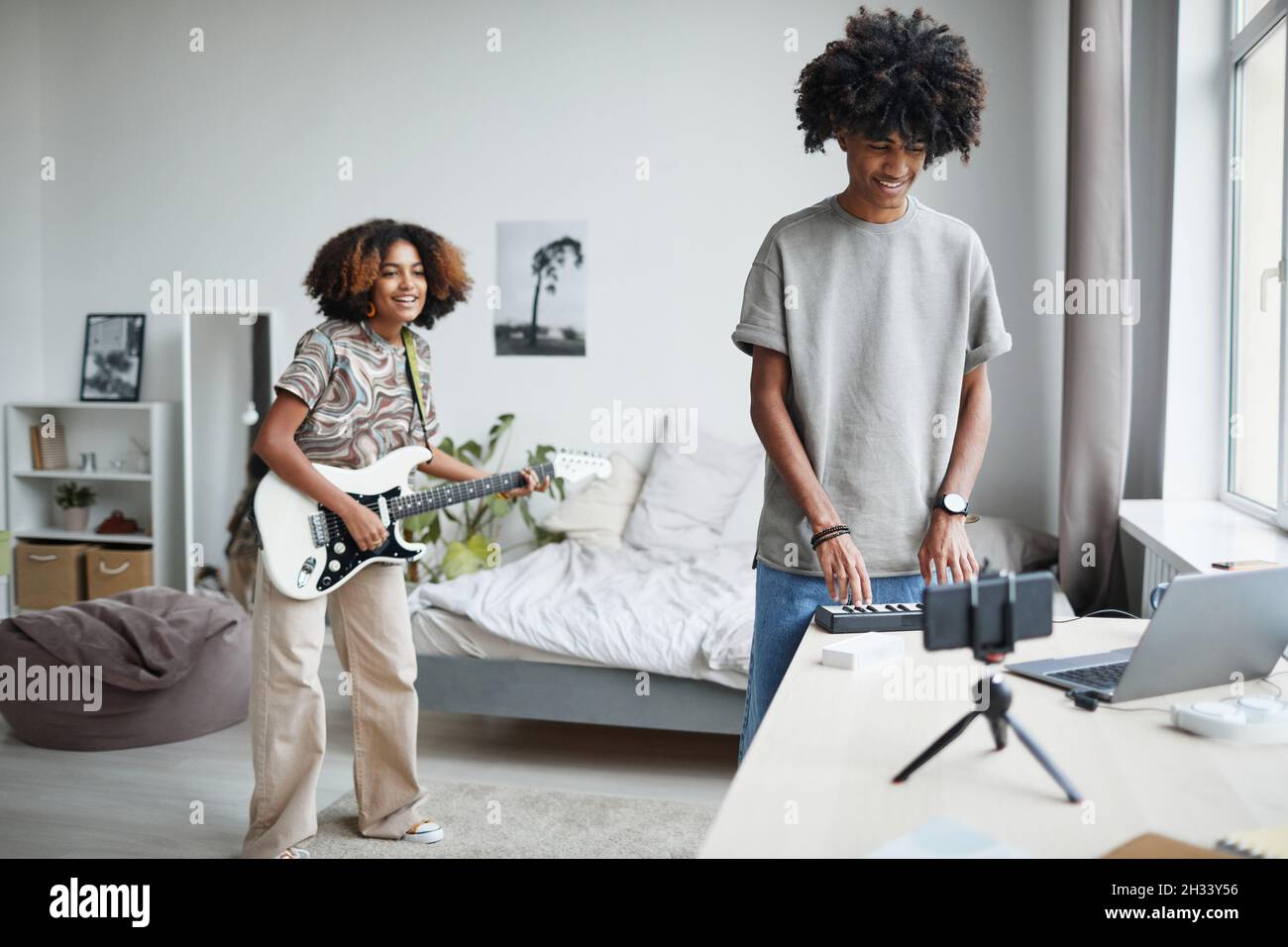 Porträt zweier afroamerikanischer junger Menschen, die zu Hause Musik spielen und Video- oder Livestream-Aufnahmen, Kopierbereich Stockfoto