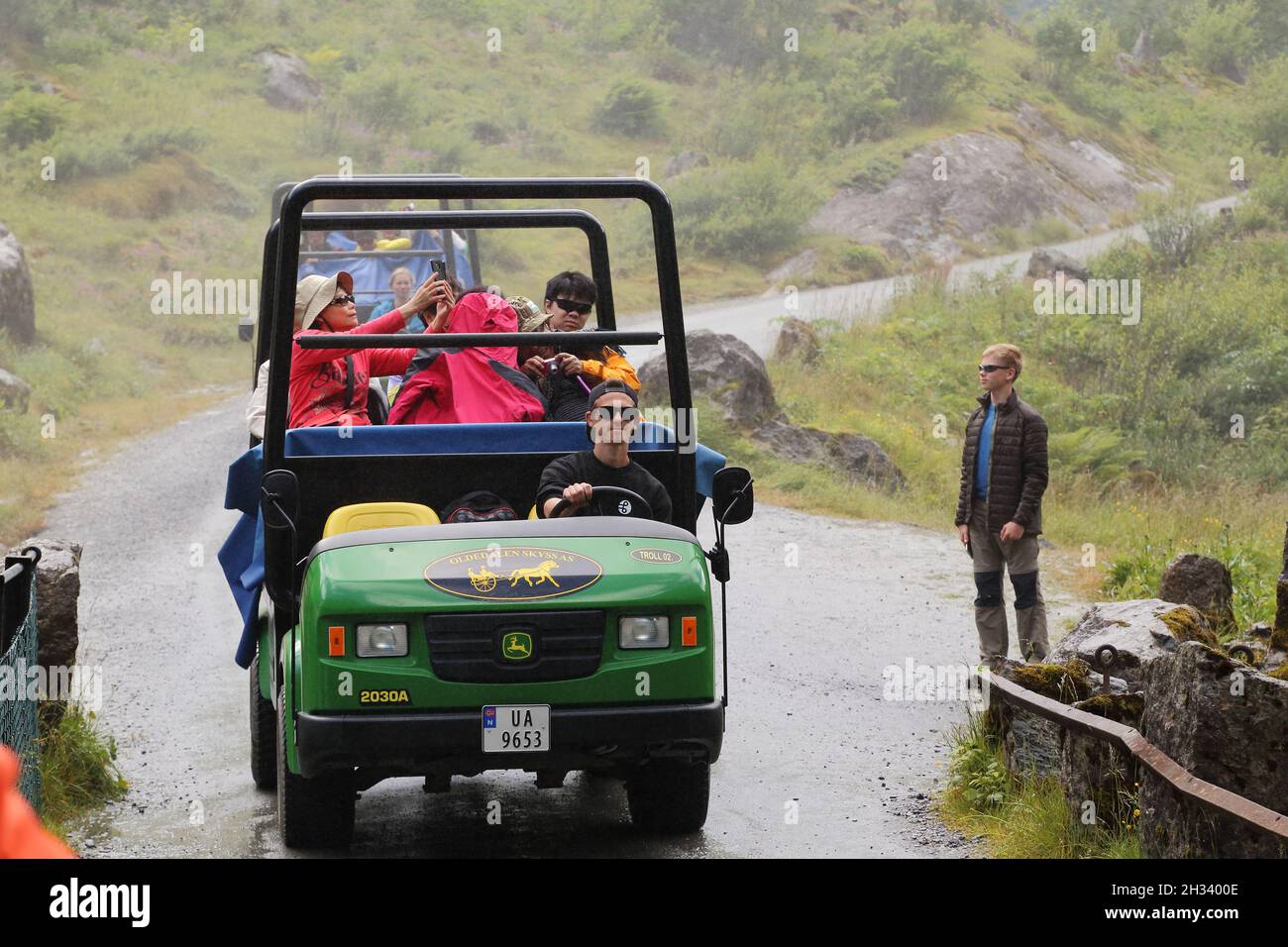 BRIKSDALSBRE, NORWEGEN - 4. JULI 2016: Spezialfahrzeug transportiert Touristen durch das Wasserfallspray zum Briksdalsbreen-Gletscher. Stockfoto BRIKSDALSBRE, NORWEGEN - 4. JULI 2016: Spezialfahrzeug transportiert Touristen durch das Wasserfallspray zum Briksdalsbreen-Gletscher. Stockfoto