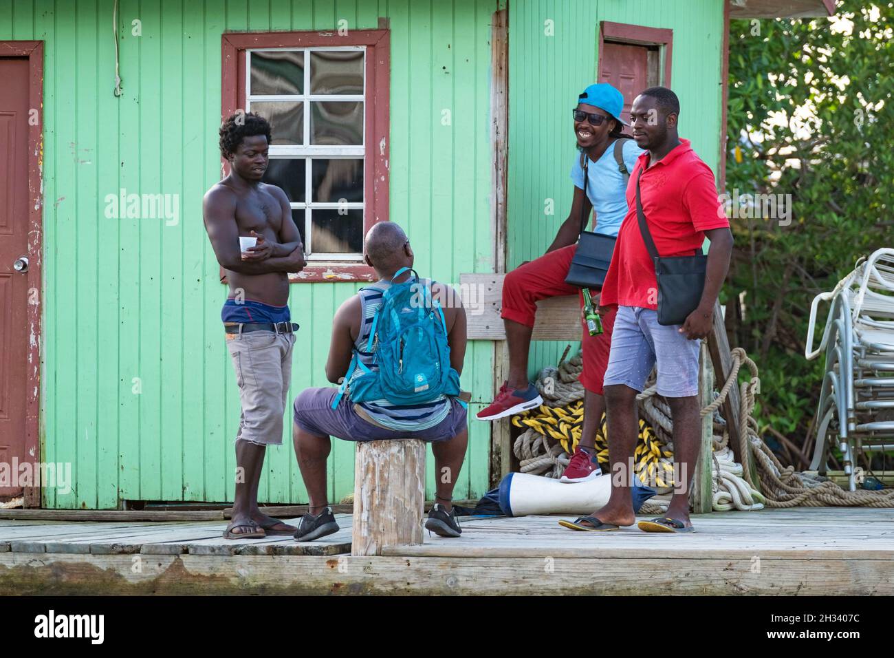 An den bunten hölzernen Docks in der Marigot Bay auf der Insel Saint Lucia im Karibischen Meer versammeln sich einheimische schwarze Männer Stockfoto