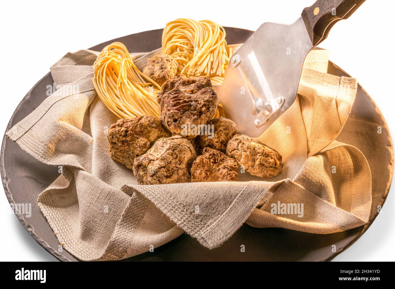 Alba weiße Trüffel in Serviette mit rohem Ei Tagliolini und Inox Stahl Trüffel Slicer in Balck Schieferplatte isoliert auf weißem Hintergrund Stockfoto