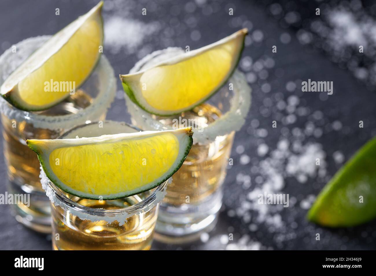 Tequila-Rand mit Salz und Kalk vor dem Hintergrund anderer Schnapsgläser geschossen. Selektiver Fokus Stockfoto