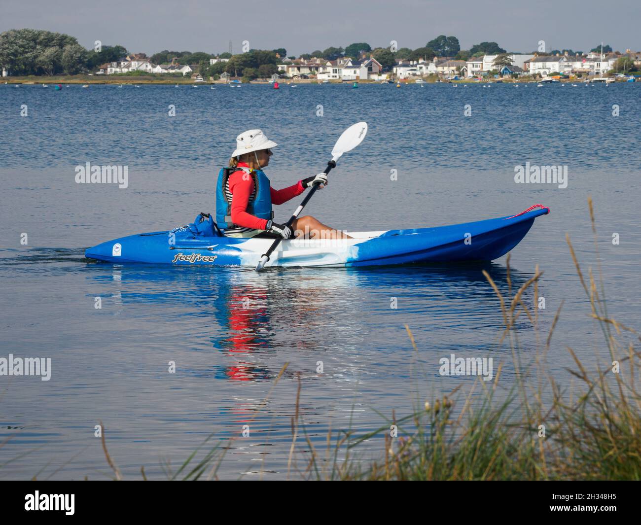 Frau mittleren Alters, die im Christchurch Harbour, Dorset, Großbritannien, mit dem Kajak unterwegs ist Stockfoto
