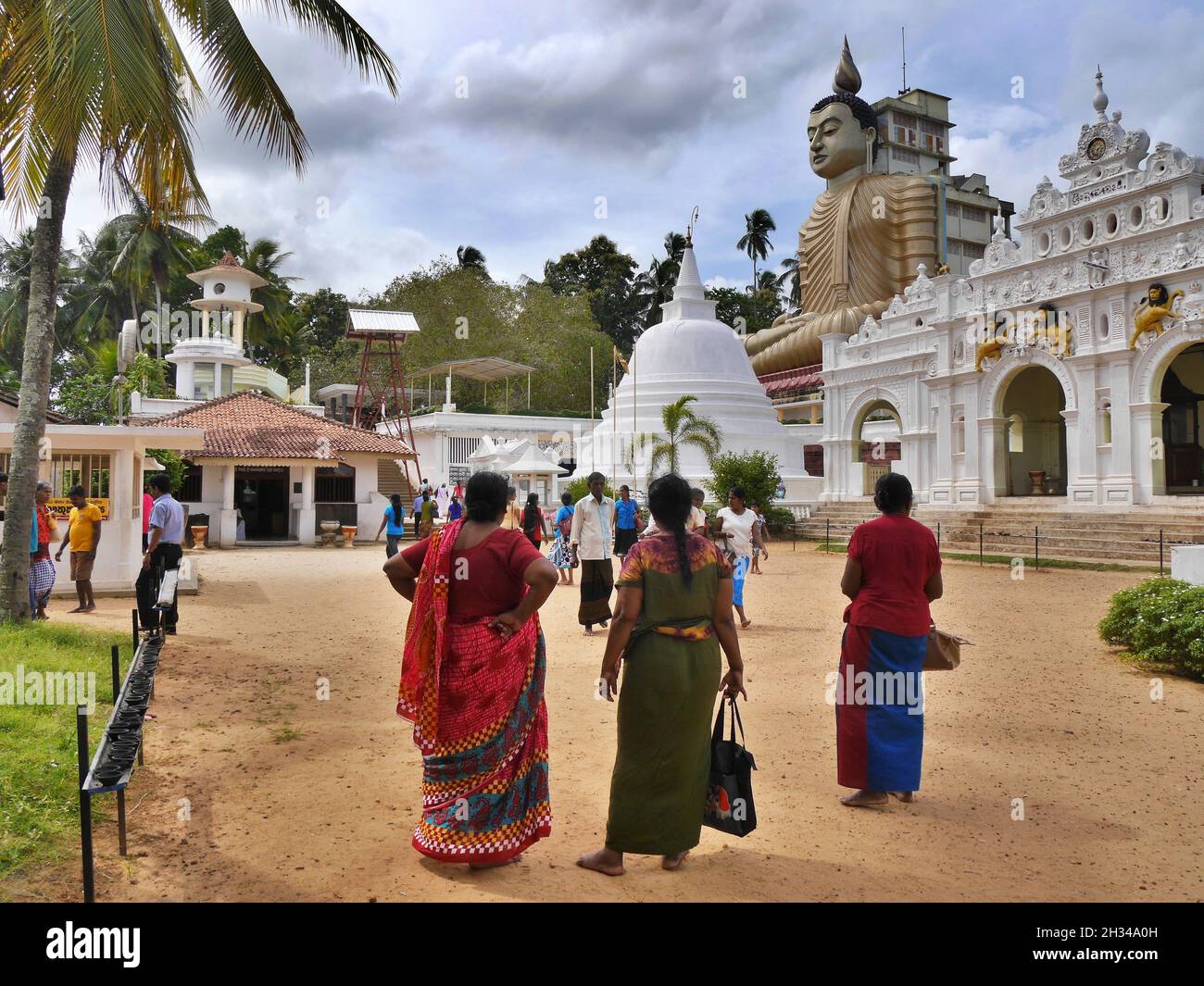 Einheimische Frauen im Dickwella-Tempel, Sri Lanka mit einer hohen Buddha-Statue. Hochwertige Fotos Stockfoto