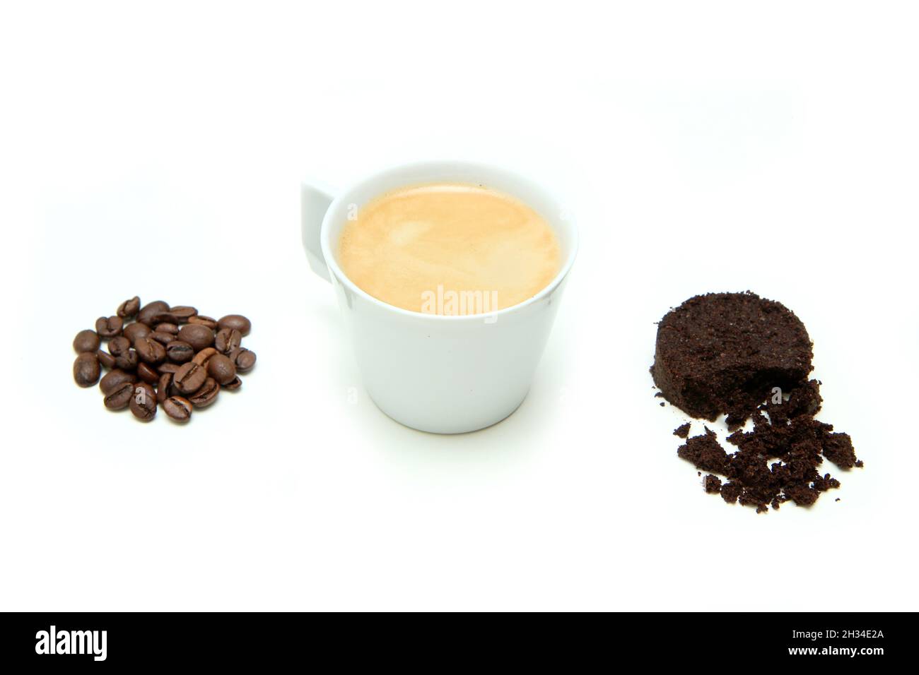 Der Espresso-Kaffee in einer kleinen Tasse zusammen mit einem kleinen Stapel Kaffeebohnen und verwendeten Kaffeesatz in einer Kapsel isoliert auf weißem Hintergrund. Stockfoto