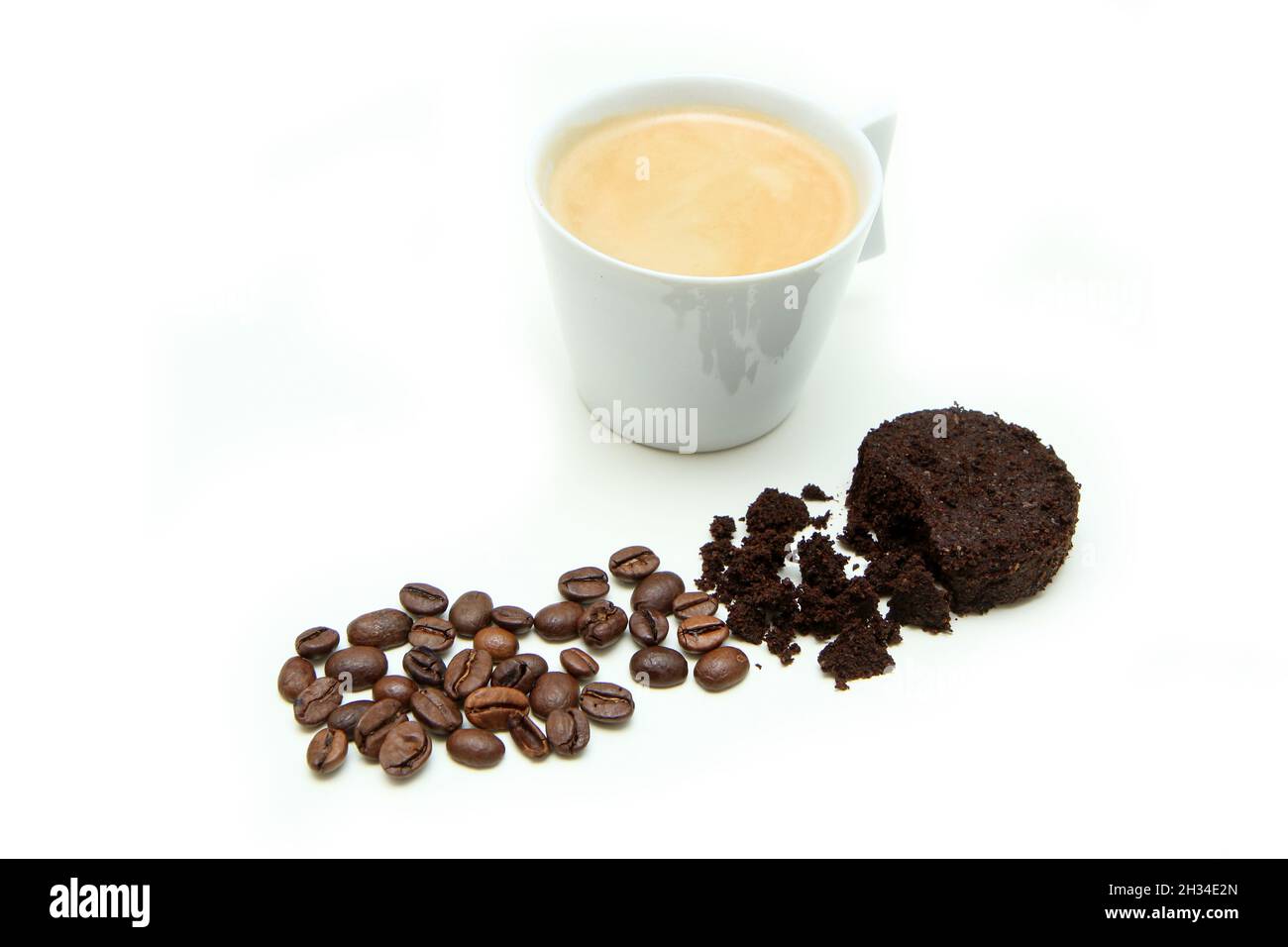 Der Espresso-Kaffee in einer kleinen Tasse zusammen mit einem kleinen Stapel Kaffeebohnen und verwendeten Kaffeesatz in einer Kapsel isoliert auf weißem Hintergrund. Stockfoto