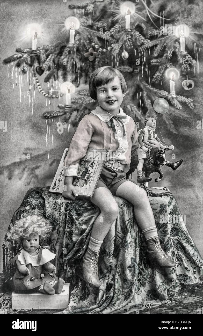 Glückliches Kind mit Weihnachtsbaum, Geschenke und Vintage-Spielzeug. Antikes Bild mit original Filmkörnung Stockfoto