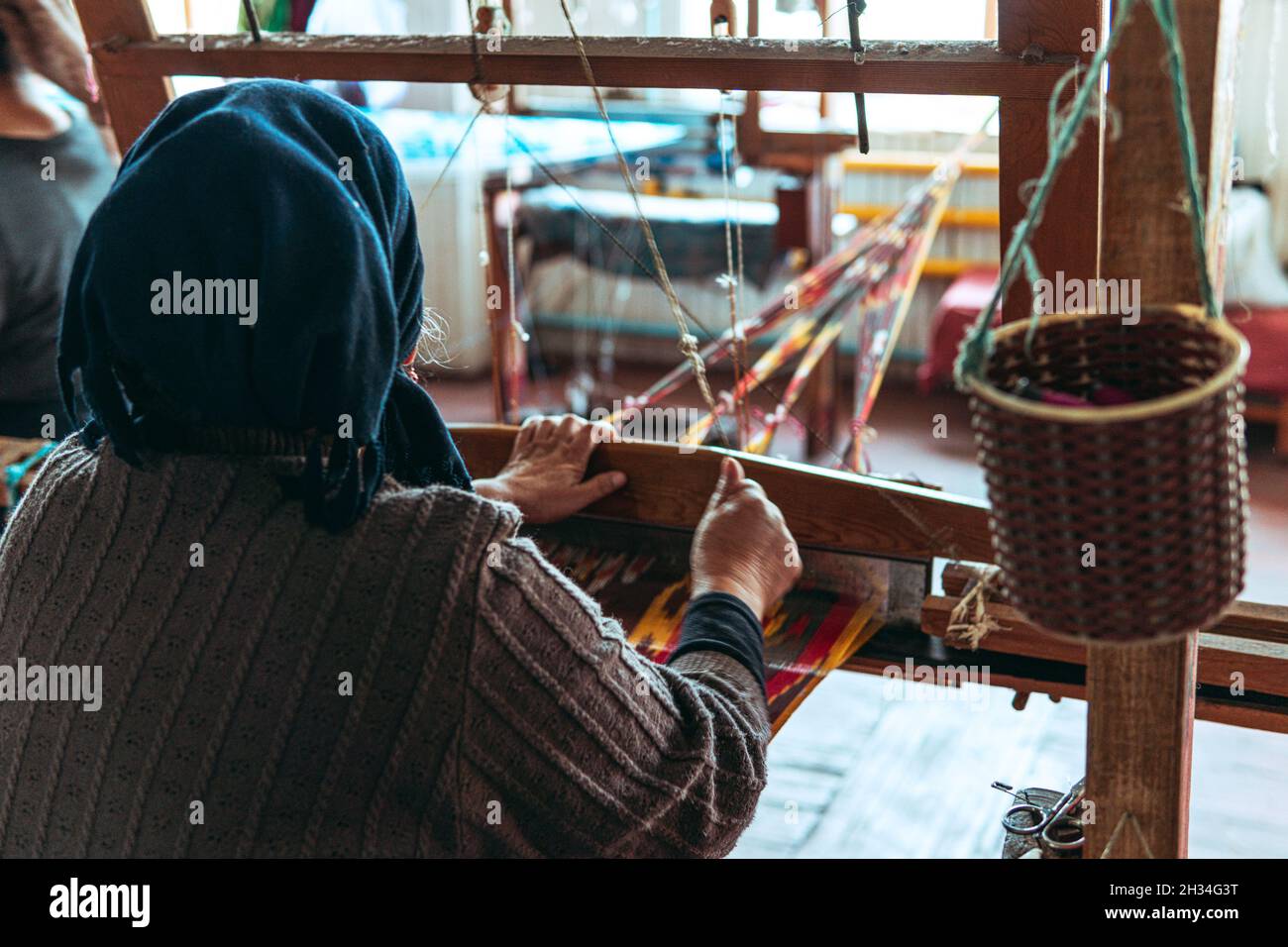 Frau, die einen Stoff mit einem traditionellen Tretwebstuhl webt. Handgefertigte Handwerkskunst Stockfoto