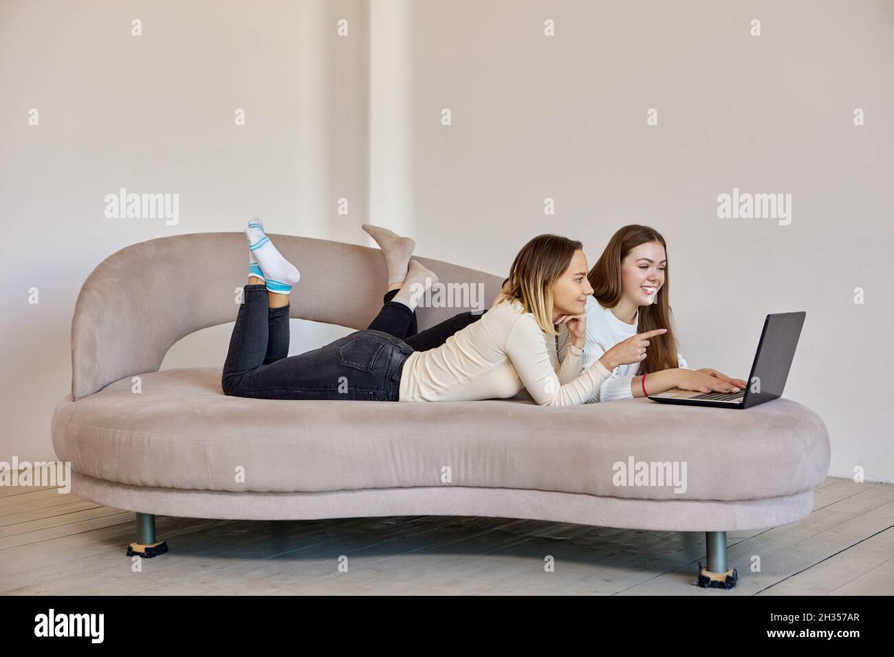 Weibliche Nachbarn schauen sich Filme mit Hilfe eines Laptops in der Lounge an. Stockfoto