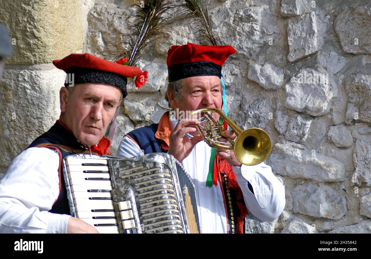 Zwei ältere polnische Männer in traditionellen polnischen Outfits spielen Akkordeon und Trompete auf der Straße in der Altstadt von Krakau, Polen. Stockfoto