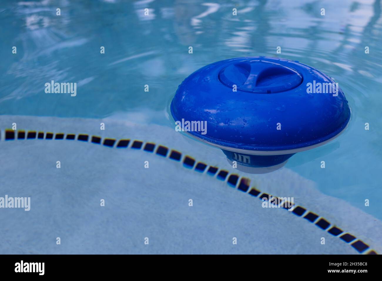 Blauer Chlorspender aus Kunststoff, schwimmend auf der Oberfläche eines Schwimmbeckens. Stockfoto