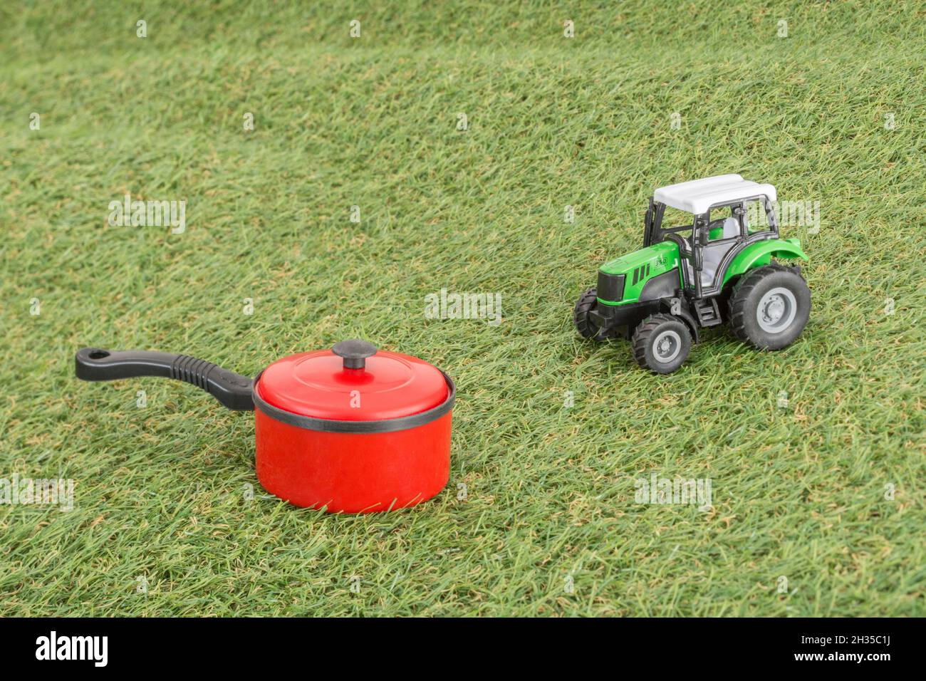 Kleiner Spielzeugtopan auf faux/fake Grass mit Edelstahlgabelzinken. Für die britische Lebensmittelproduktion: Farm to Fork, Field to Fork / Field to Plate Idiome. Stockfoto