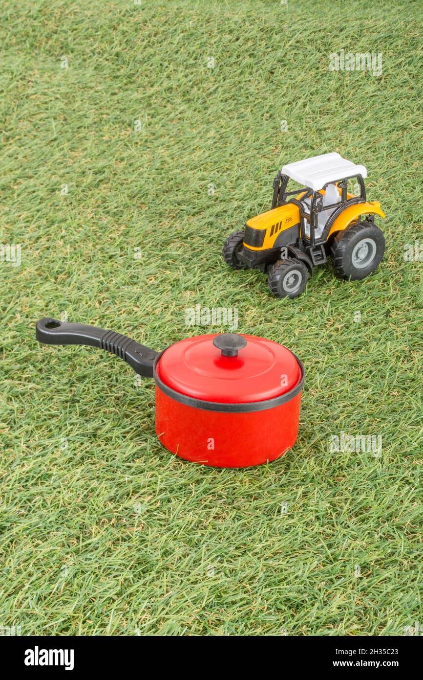 Kleiner Spielzeugtopan auf faux/fake Grass mit Edelstahlgabelzinken. Für die britische Lebensmittelproduktion: Farm to Fork, Field to Fork / Field to Plate Idiome. Stockfoto