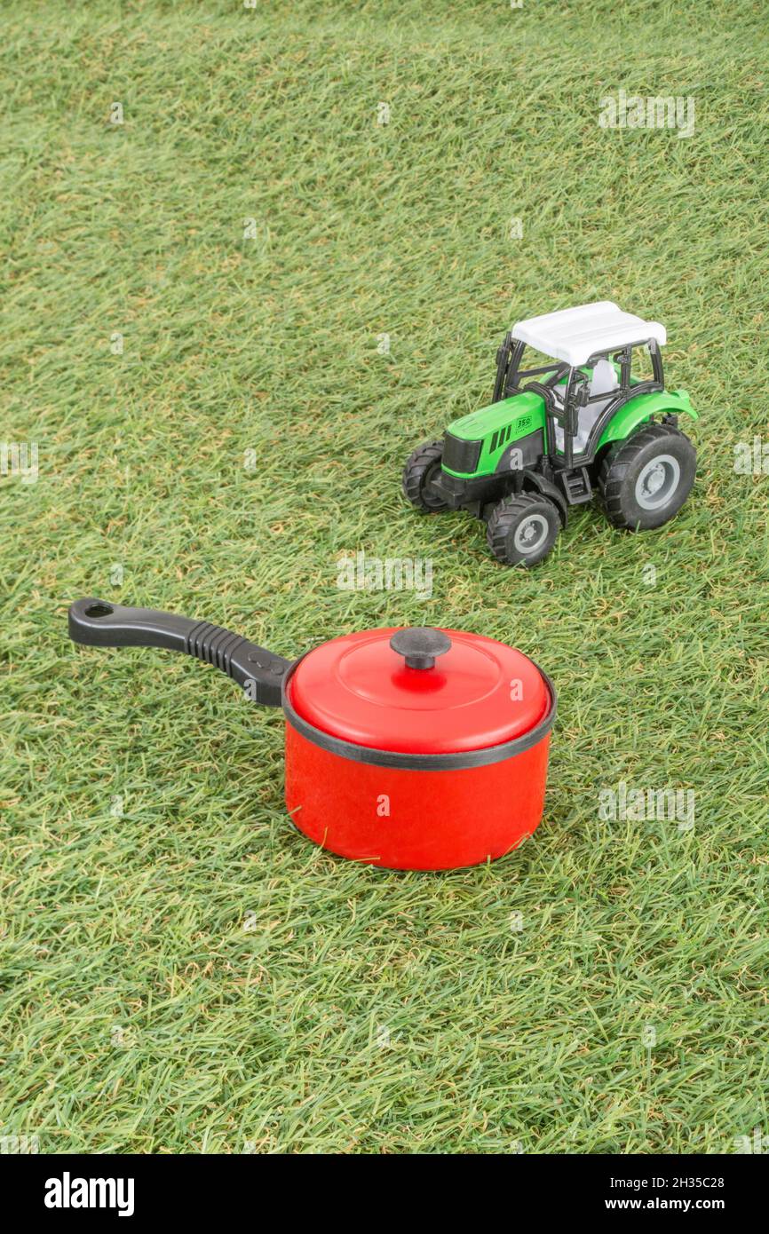 Kleiner Spielzeugtopan auf faux/fake Grass mit Edelstahlgabelzinken. Für die britische Lebensmittelproduktion: Farm to Fork, Field to Fork / Field to Plate Idiome. Stockfoto