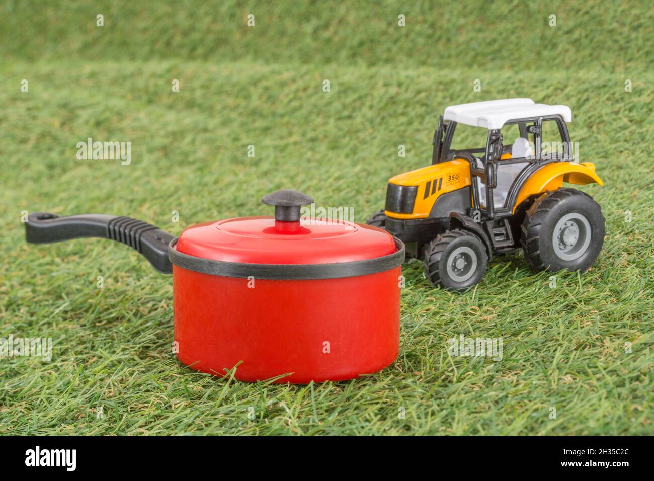 Kleiner Spielzeugtopan auf faux/fake Grass mit Edelstahlgabelzinken. Für die britische Lebensmittelproduktion: Farm to Fork, Field to Fork / Field to Plate Idiome. Stockfoto