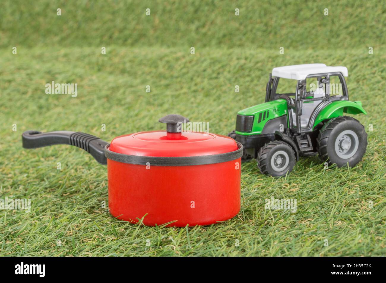 Kleiner Spielzeugtopan auf faux/fake Grass mit Edelstahlgabelzinken. Für die britische Lebensmittelproduktion: Farm to Fork, Field to Fork / Field to Plate Idiome. Stockfoto