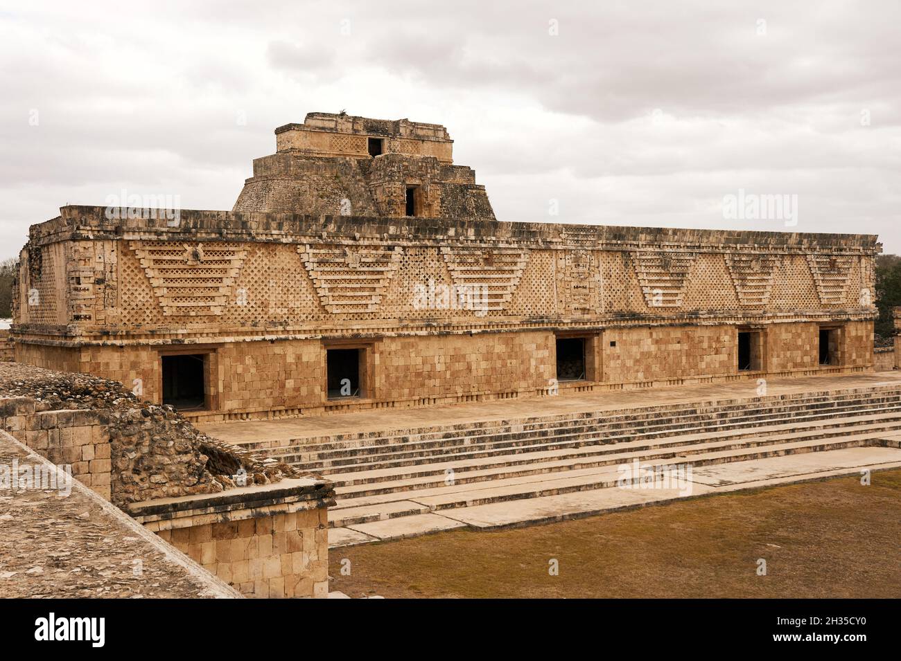 Ostgebäude des Nunnery Quadrangle mit der Pyramide des Magiers, die im Hintergrund bei den Maya-Ruinen von Uxmal, Yucatan, Mexiko, aufsteigt Stockfoto