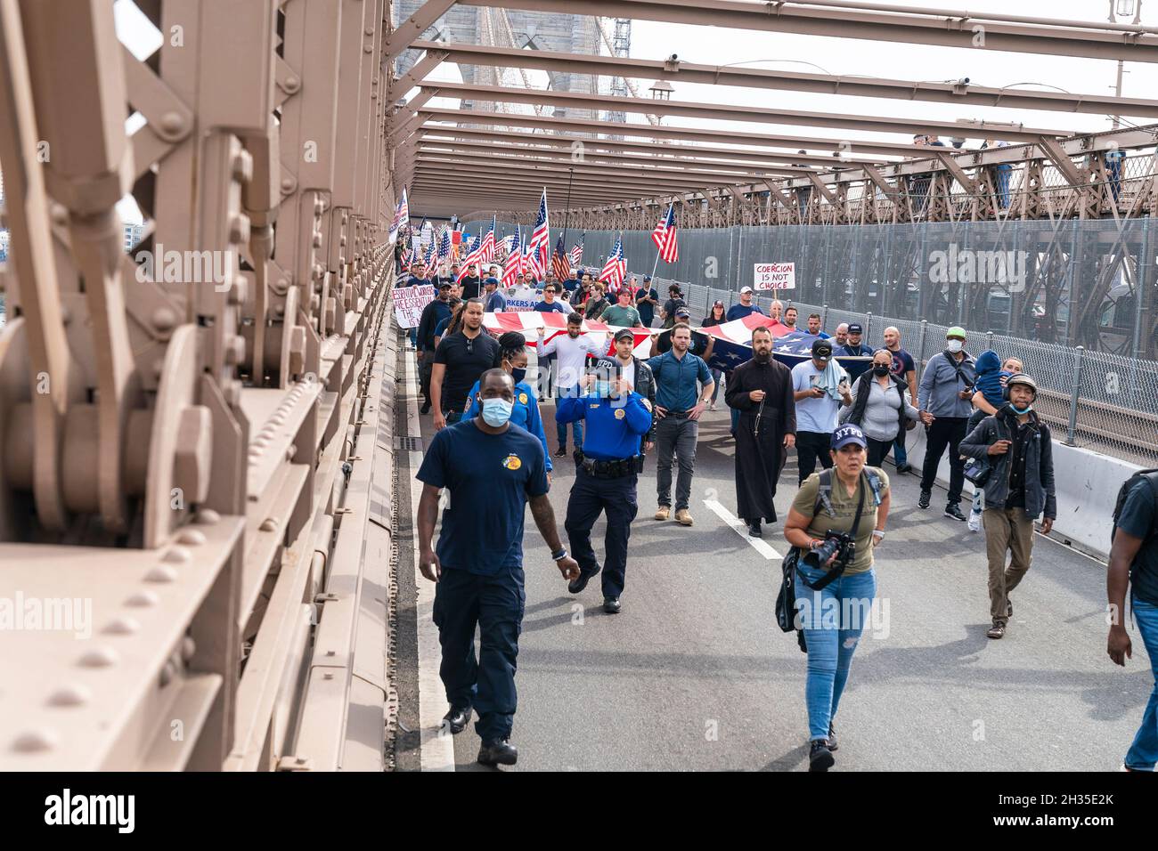 Der katholische Priester aus der Staten Island Kirche führt die städtischen Arbeiter der Stadt marschieren über die Brooklyn Bridge und versammeln sich am 25. Oktober 2021 im City Hall Park gegen das Impfmandat in New York. Angestellte der Stadtverwaltung von New York Police Department, Sanitation Department, Fire Department, Department of Education, Department of Correction, Parks Department, City Health and Hospitals, Metropolitan Transit Authority und andere städtische Büroangestellte, die vom Bürgermeister beauftragt wurden, sich bis zum 1. November 2021 gegen die COVID-19-Krankheit impfen zu lassen, oder sie werden außer Arbeit und aus dem Gehaltsscheck gelassen. (Foto von Lev Radin/Sipa U Stockfoto