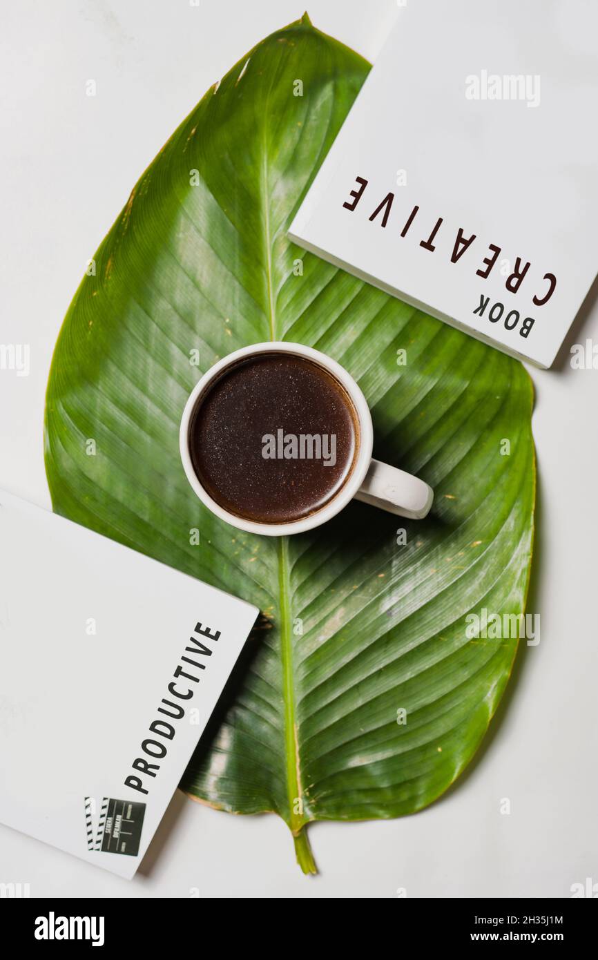 Coffee, ein Buch mit kreativen und produktiven Worten und grünen Blättern Stockfoto