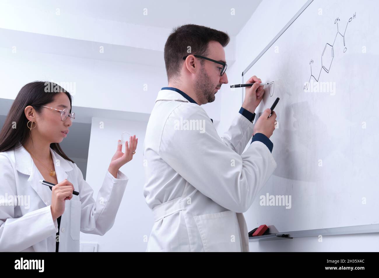 Zwei zahnärztliche Forscher untersuchen die Zahnanatomie auf einem Whiteboard. Stockfoto