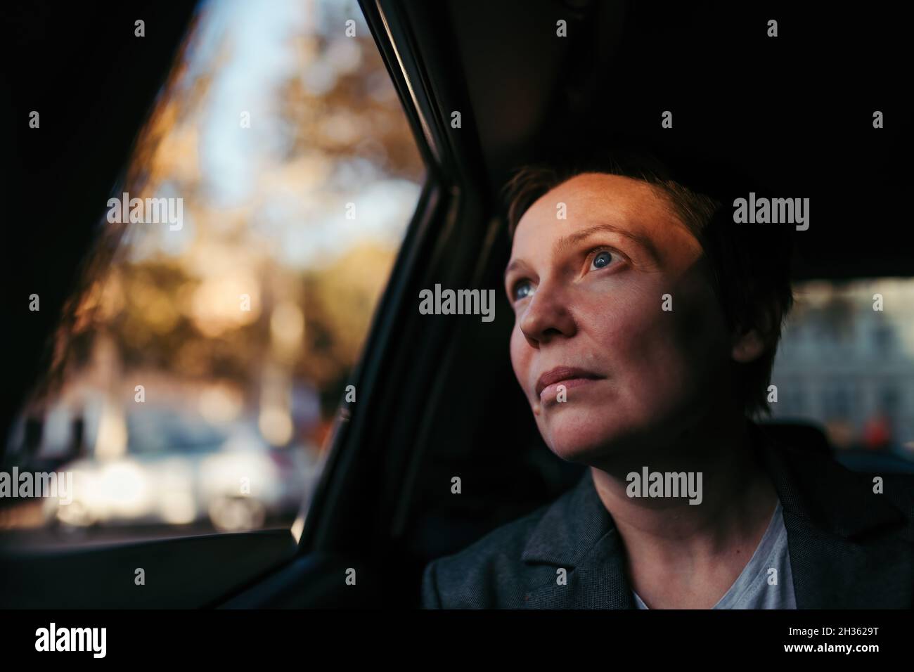 Hoffnungsvolle Geschäftsfrau, die aus dem Autofenster in den Himmel schaut, Hoffnung und Antizipation Konzept, selektiver Fokus Stockfoto