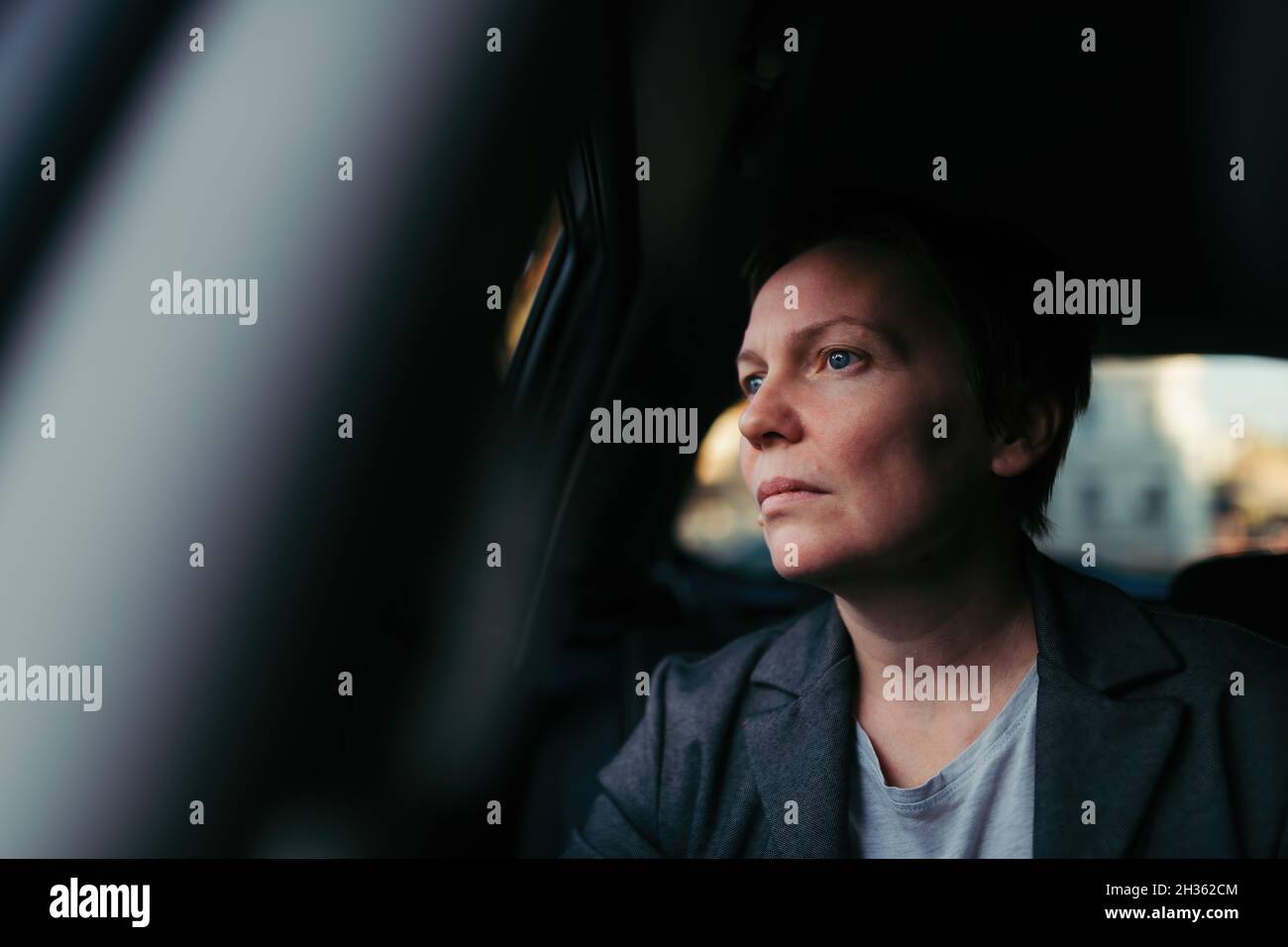 Besorgte Geschäftsfrau, die im Auto wartet und aus dem Fenster schaut, selektiver Fokus Stockfoto