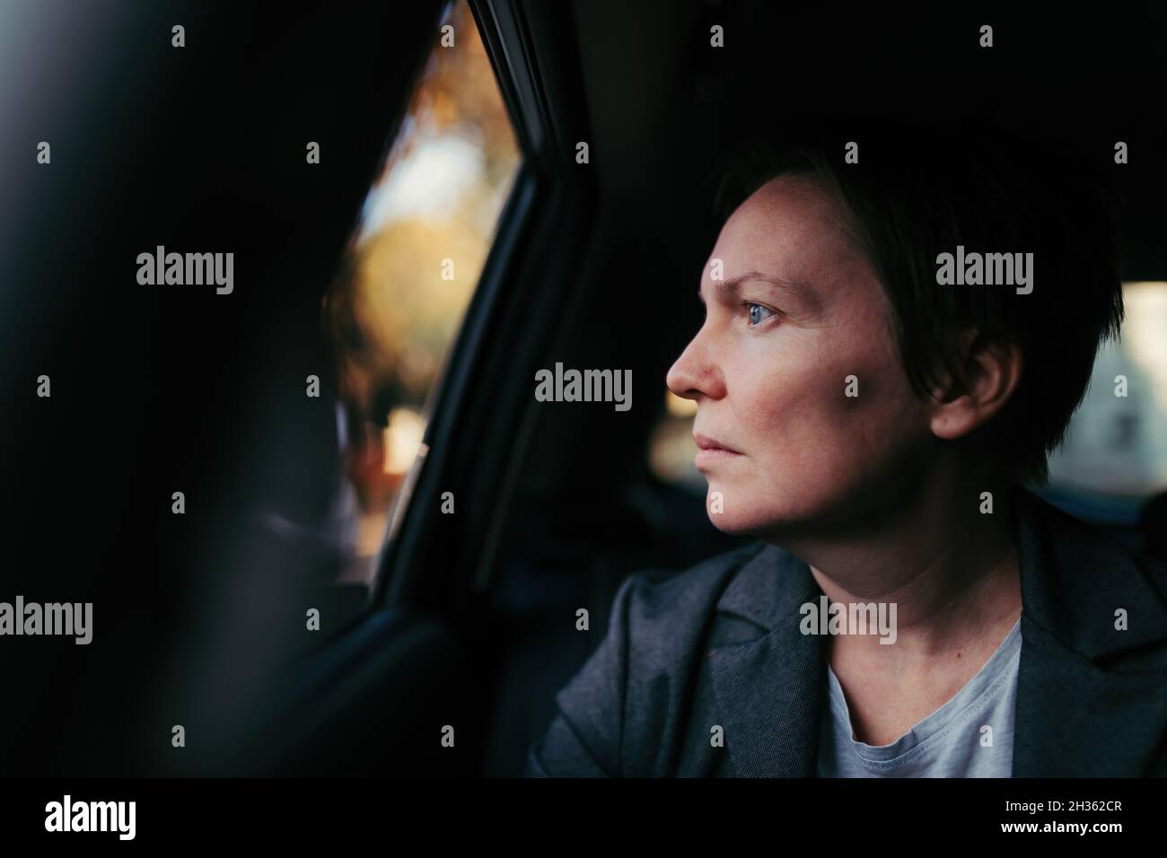 Besorgte Geschäftsfrau, die im Auto wartet und aus dem Fenster schaut, selektiver Fokus Stockfoto