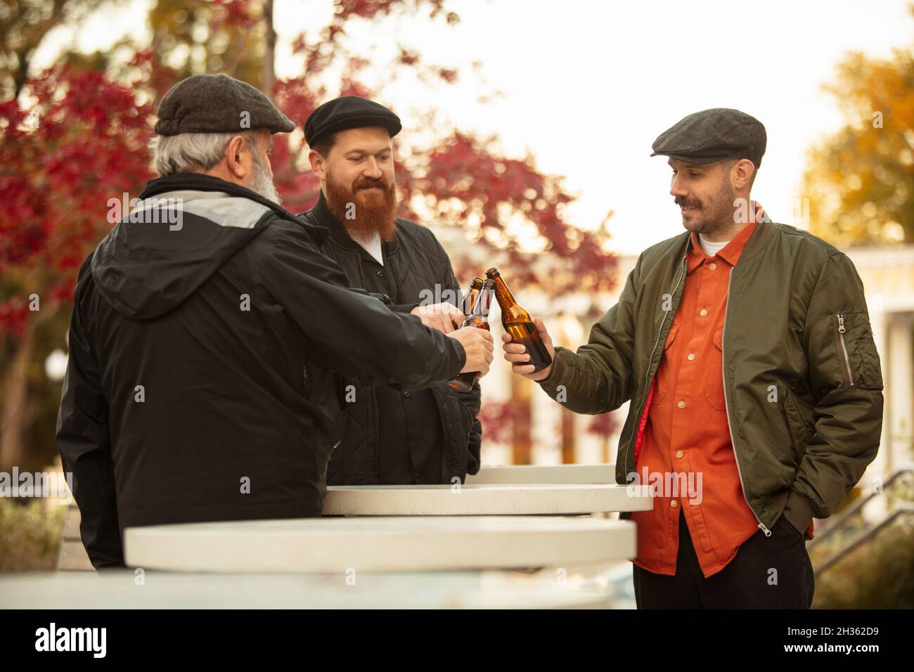 Gruppe von Männern, Freunden, Nachbarn verbringen Zeit zusammen im Freien an warmen Herbsttag. Bier trinken Stockfoto