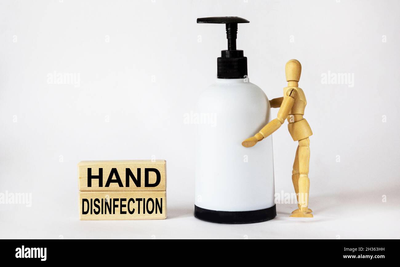 Händedesinfektion, Text ist auf Holzklötze geschrieben.Holzpuppe mit Alkoholspray zur Händedesinfektion. Stockfoto