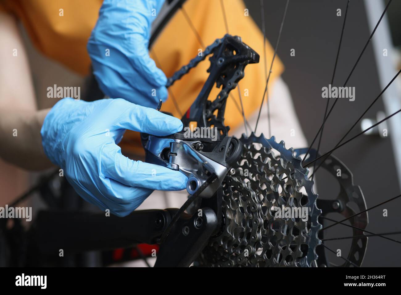Handyman in Gummihandschuhen zur Befestigung von Bremsen von Fahrrad Nahaufnahme. Reparatur und Wartung von Fahrrädern Konzept Stockfoto