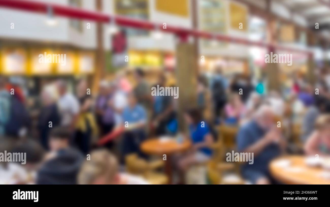 Verschwommenes Hintergrundbild von Menschen, die in einem belebten Food Court mit Restaurants essen. Stockfoto